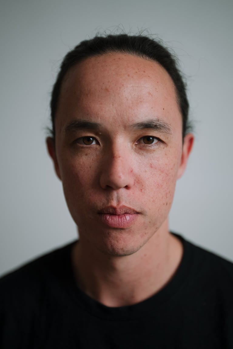 Portrait of a man with dark hair and beard stubble wearing a black shirt